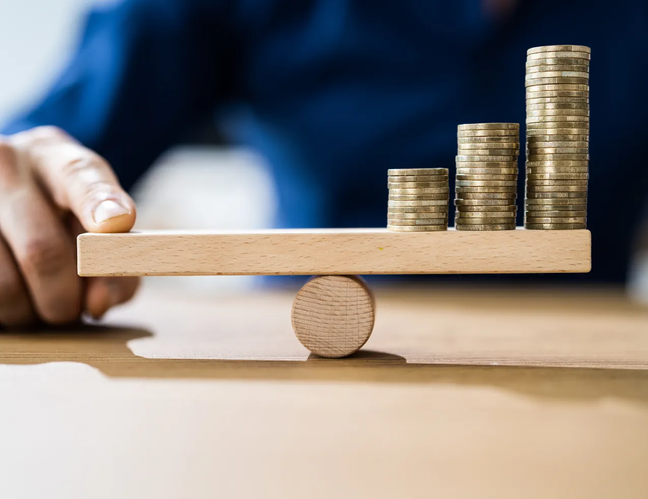 Image of coins balanced on a wooden lever symbolizing the concept of leverage: balancing opportunities for profit and risk of loss.